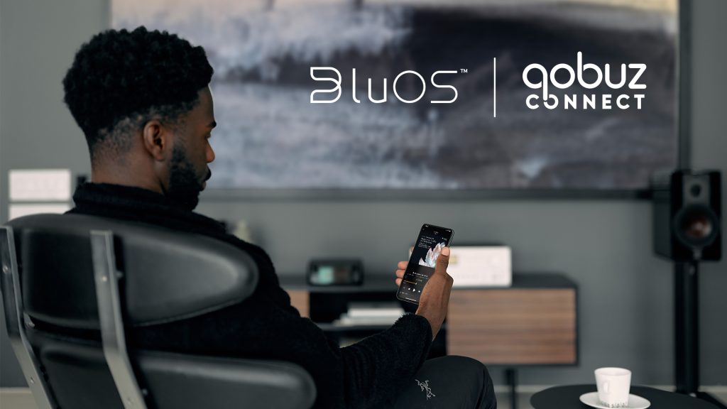 A person holding a phone with BluOS app open